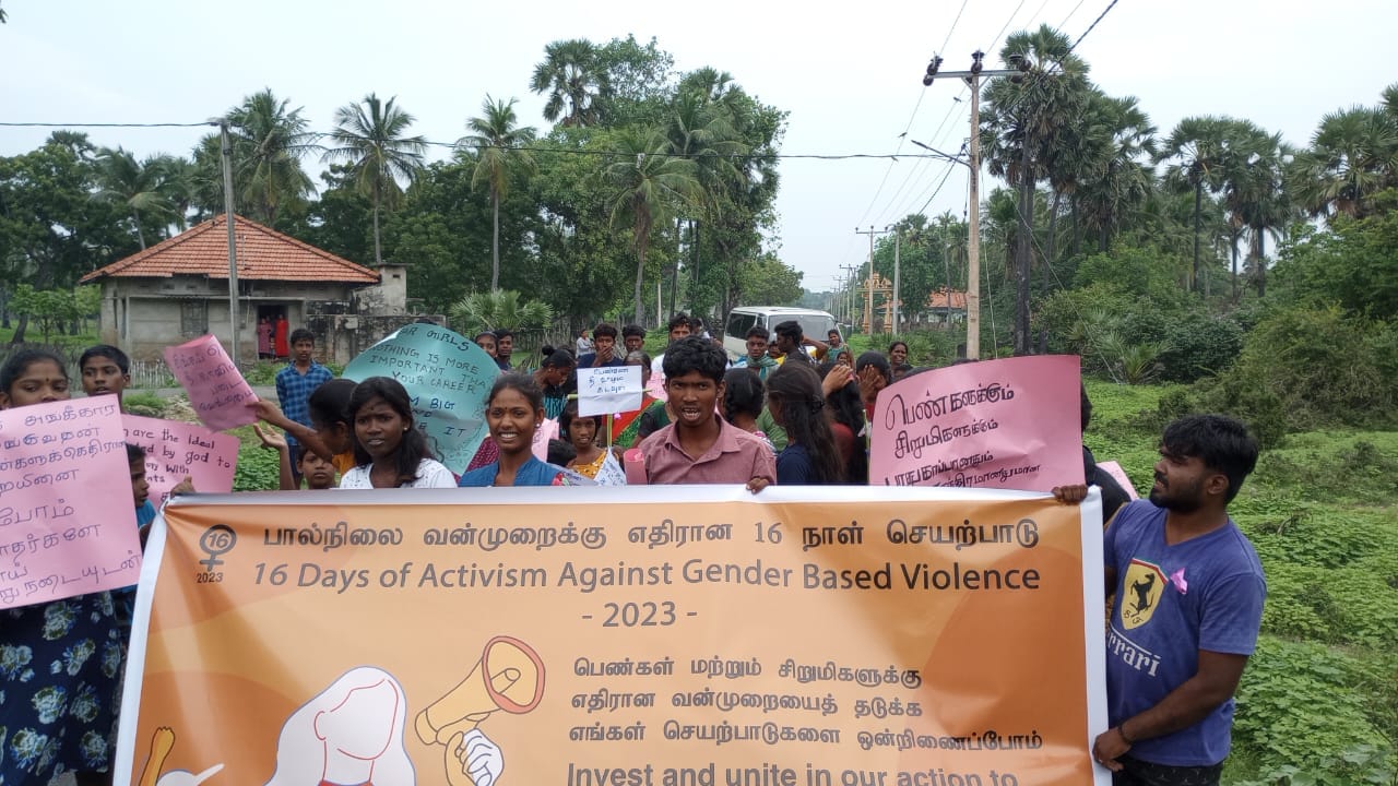 Community members walking together with banner for 16 days of activism